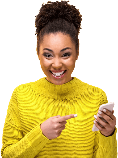 A smiling woman in a bright yellow sweater pointing to her mobile phone.